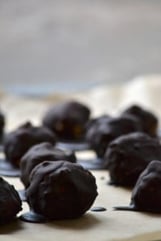 Chocolate covered cookie dough bites on a grey background.