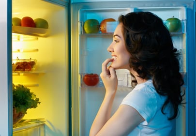 a hungry girl opens the fridge